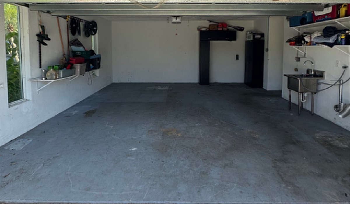 Garage floor before epoxy flake coating: stained, dusty bare concrete slab